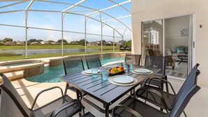 A covered outdoor area with a pool, dining table, and chairs.