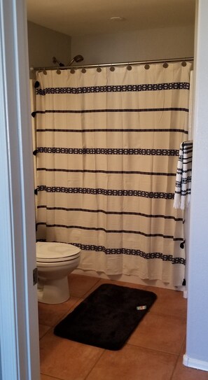 Een bad/douchecombinatie, een haardroger, handdoeken, zeep