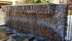 Mur de pedra amb una font, incloent una cascada i una bassa amb roques.