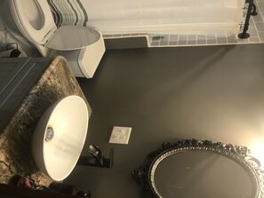 Bathroom features a toilet, sink, and mirror with ornate frame, set against a tiled floor.