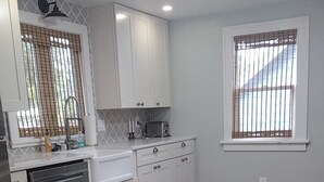 A modern kitchen with white cabinets, a dishwasher, and a tiled floor. - Cozy 3 Bedroom Port Clinton House (Port Clinton)