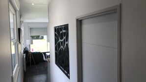 Um corredor com uma porta de garagem fechada, uma parede branca e uma janela com persianas.
