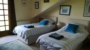 A bedroom with two beds, a window, and a radiator. - Perfectly located for The Pentlands. It also has easy access to the city. (Edinburgh)