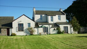 A two-story house with a well-maintained lawn and a patio area with outdoor furniture. - Perfectly located for The Pentlands. It also has easy access to the city. (Edinburgh)