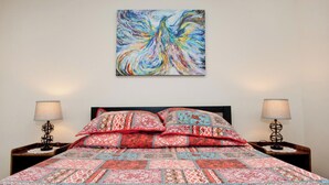 A bed with patterned bedding, two bedside lamps, and a colorful abstract painting on the wall. - Modern Industrial, 12 min walk to Bridge St. (Phoenixville)