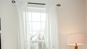 A living room with a sofa, colorful pillows, a lamp, a plant, and a window with curtains. - Modern Industrial, 12 min walk to Bridge St. (Phoenixville)