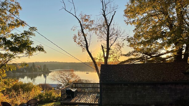 A lakeside view with a wooden deck, a brick wall, and a grassy area with chairs. - Cozy Cottage   with spectacular salt water  view / 4 Kayaks available/ (Bremen)