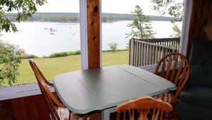 A wooden deck with a table and chairs overlooking a lake. - Cozy Cottage   with spectacular salt water  view / 4 Kayaks available/ (Bremen)