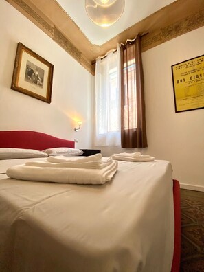 A hotel room with two beds, a red headboard, a framed picture on the wall, a window with curtains, and a poster on the wall. - Al Teatro B&B (Reggio Calabria)