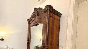 Een houten garderobe met spiegel, een klein kaptafeltje en een betegelde vloer.