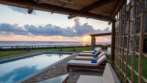 A poolside area with lounge chairs and a view of the sunset over the ocean. - VILLA KORE ELAFONISSI (Keramoti)