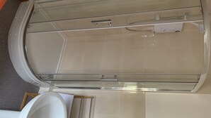 A bathroom with a glass shower enclosure, a white sink, and a wooden frame.