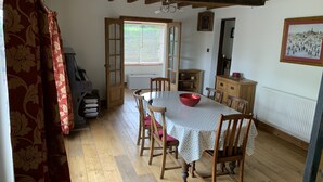 A dining area with a wooden table and chairs, a red bowl on the table, and a wooden cabinet in the background.