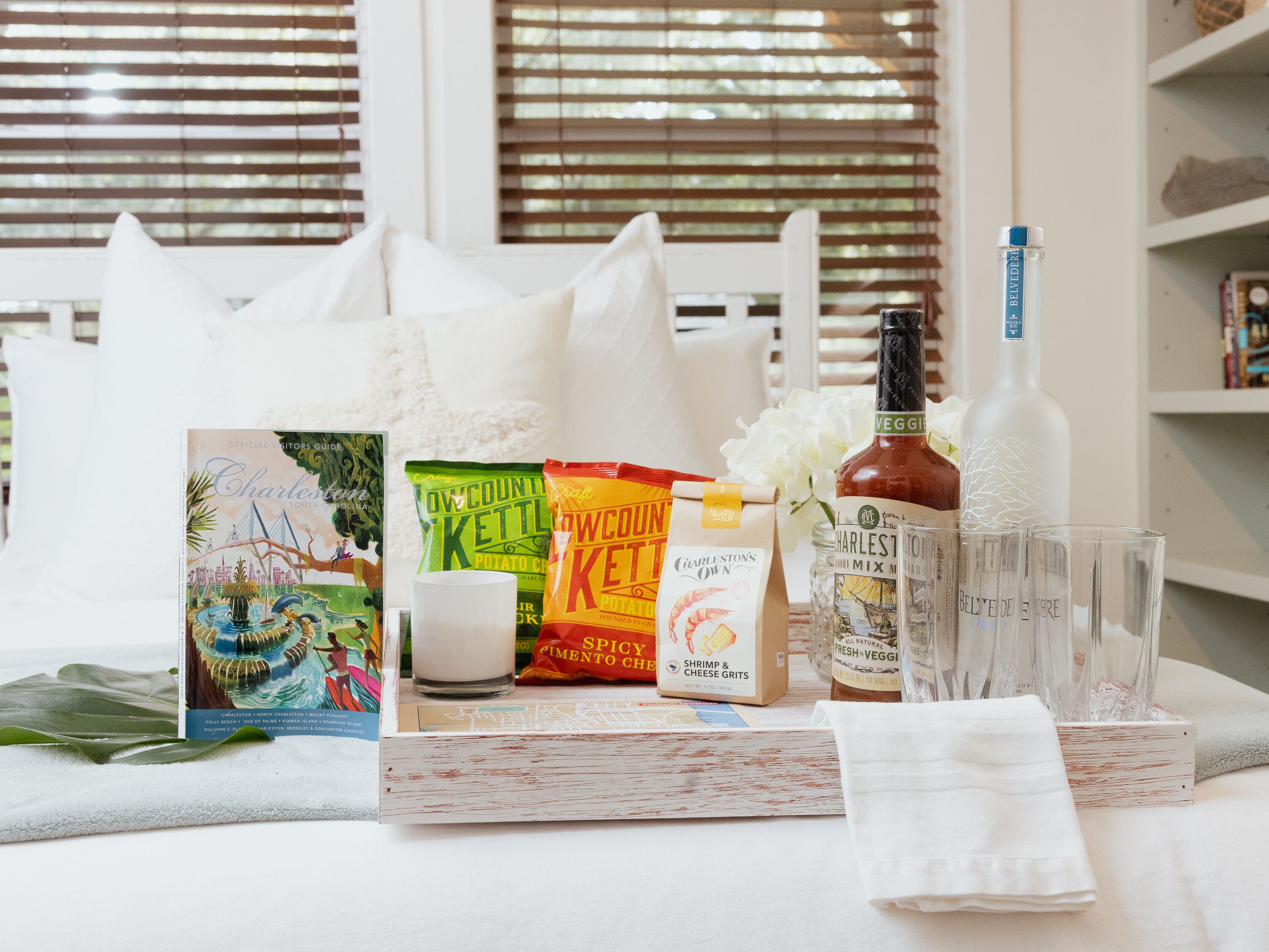 Ein ordentlich gedeckter Tisch mit einem Buch, Snacks, einer Flasche und Gläsern.