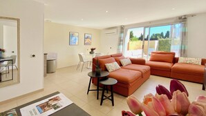 Een moderne woonkamer met een zithoek, een eethoek en een groot raam met uitzicht.
