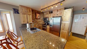 Una cocina con encimeras de granito, armarios de madera y electrodomésticos de acero inoxidable, además de una isla integrada.