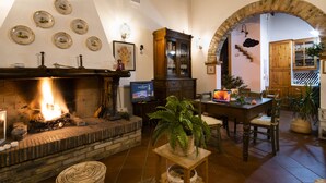 A cozy living room with a fireplace, wooden furniture, and a stone archway.