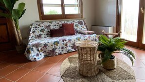 A cozy living room with a sofa, a round wicker table, and a potted plant.