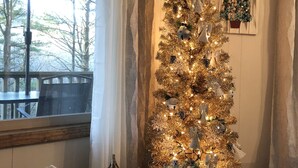 Ein Weihnachtsbaum in einem Zimmer mit Blick auf Bäume draußen.