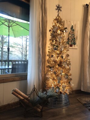 Ein Weihnachtsbaum in einem Zimmer mit Blick auf Bäume draußen.