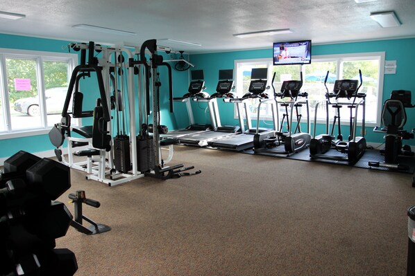 A gym with cardio machines, weightlifting equipment, and a television screen. - Sky Valley Mountain Cabin (Sky Valley)