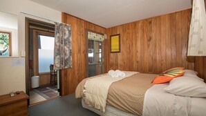 Una camera da letto con un letto, pareti in legno, una porta, un tavolino e una sedia.