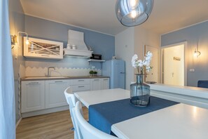 A modern kitchen with white cabinets, a blue countertop, and a dining table with a vase of flowers.