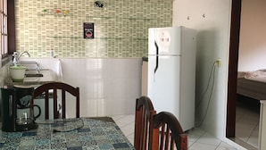 A kitchen with a tiled backsplash, a refrigerator, a coffee maker, and a dining table with chairs.