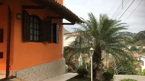 A house with a tiled roof, a tiled porch, and a small garden with a palm tree.