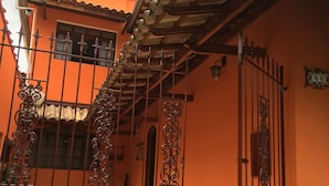 A building with a tiled roof, a gated entrance, and a number sign indicating the address.
