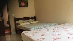 A bedroom with two beds, a wooden headboard, and a floral painting on the wall.