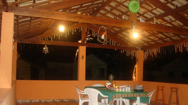 A covered outdoor dining area with a table set for four, surrounded by white plastic chairs.