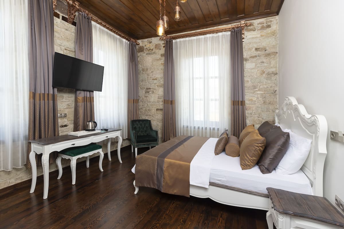 A bedroom with a bed, a desk, a chair, and a TV.