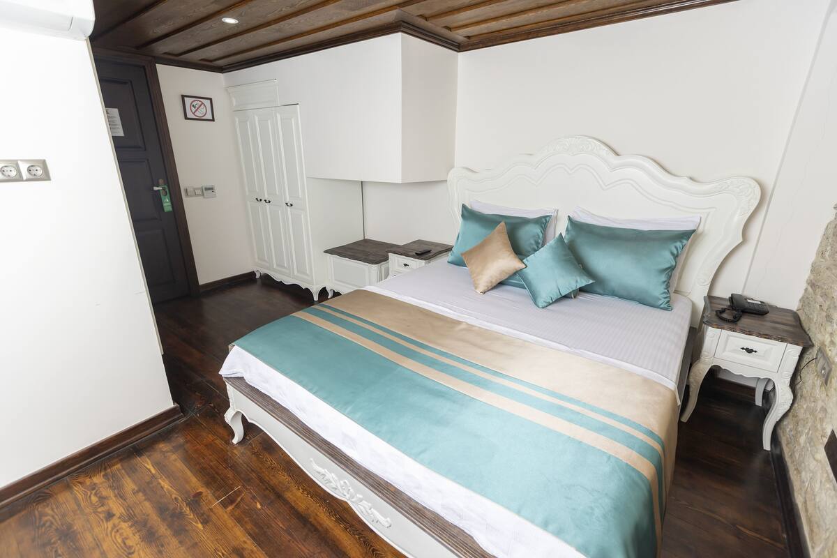 A neatly arranged bedroom with a large bed, bedside tables, a wardrobe, and a door with a 'No Entry' sign.