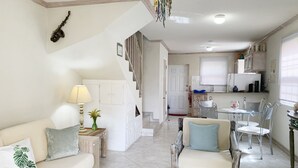 A living room with a sofa, a chair, a lamp, and a staircase leading to a kitchen area.