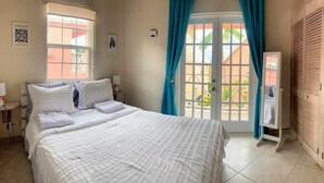 A bedroom with a bed, two bedside tables, a window with curtains, and a wooden wardrobe.
