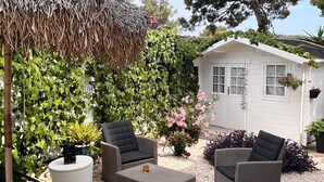 A patio area with wicker furniture, a thatched umbrella, and a small white house in the background. - Apartment Dolce Vita - 40 m to the sea & Beach-sleeps 3 (Milna)