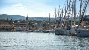 A marina with several sailboats docked, a church with a tall steeple, and a hilly landscape in the background. - Apartment Dolce Vita - 40 m to the sea & Beach-sleeps 3 (Milna)