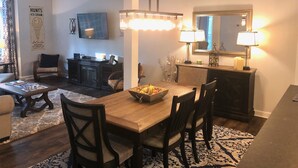 A dining area with a wooden table, four chairs, a chandelier, and a mirror above the table. - Reynolds Villa- Golf/Couples Retreat (Southern Pines)
