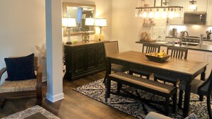 A modern kitchen with white cabinets, a wooden dining table, and pendant lighting. - Reynolds Villa- Golf/Couples Retreat (Southern Pines)