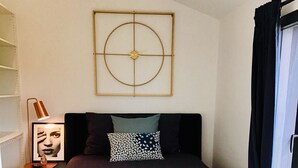 Un dormitorio con cama, alfombra, una obra de arte en la pared y una ventana con cortinas.