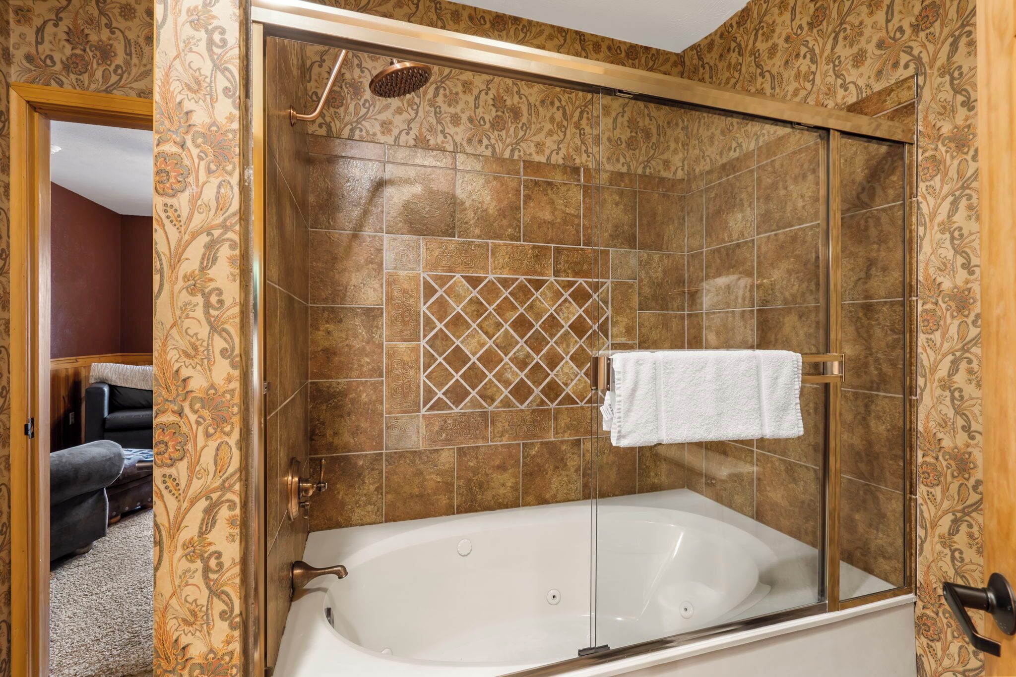Une salle de bain avec une baignoire, une douche et un mur décoré d’un motif.