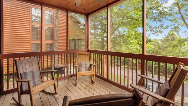 A wooden deck with rocking chairs and a table, large windows, and a ceiling fan. - "Back-Porch Sittin'" Perfect! Walk-in Cedar Cabin near 76 Country Blvd Strip! (Branson)