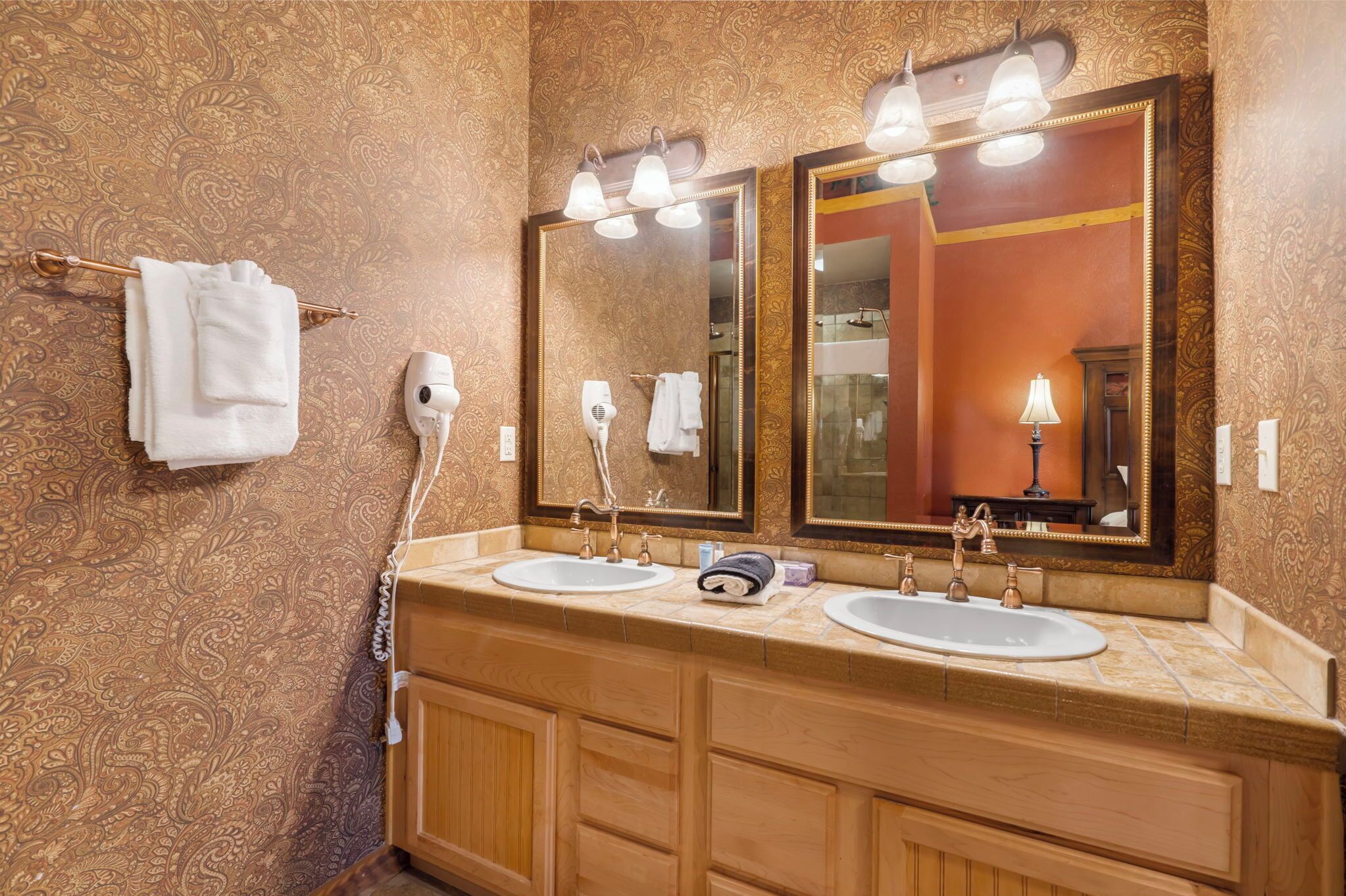 Une salle de bain avec deux lavabos, un grand miroir et un porte-serviettes avec des serviettes blanches.