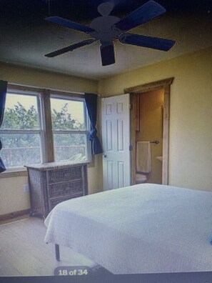 Relax in comfort with a large bed, a dresser, and a small table, all set against a light-colored backdrop.