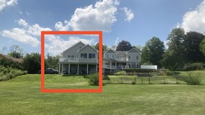 Ein zweistöckiges Haus mit einer Veranda und einem eingezäunten Garten.