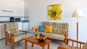 A living area with a sofa, two armchairs, a coffee table, and a fruit bowl. There is a microwave and a refrigerator in the background. - Reyes Natur - Bungalow on the seafront (Charco del Palo)
