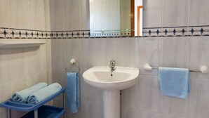 A bathroom with a sink, mirror, and blue towels on a rack. - Reyes Natur - Bungalow on the seafront (Charco del Palo)