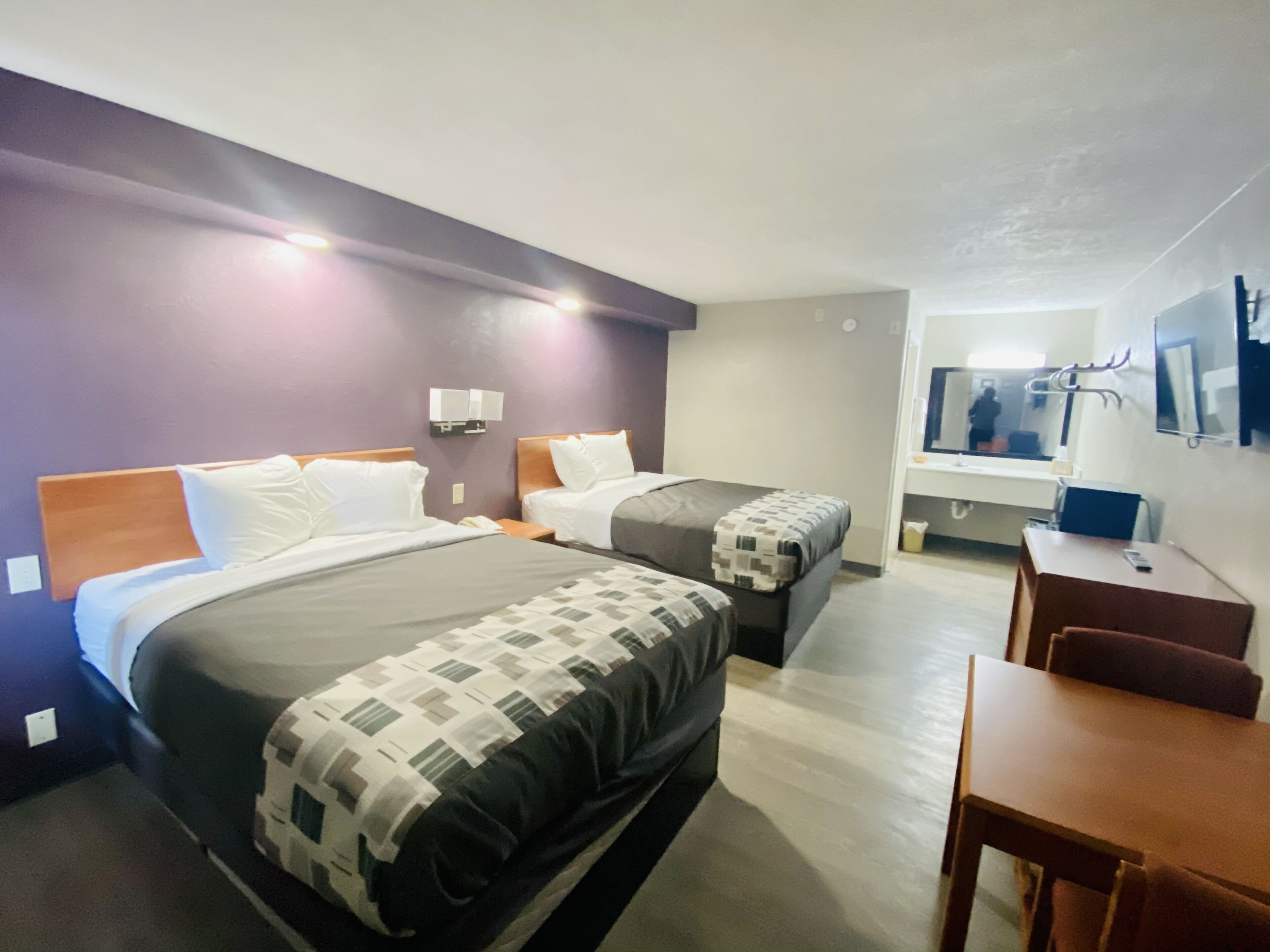 Een hotelkamer met twee bedden, een bureau en een spiegel.