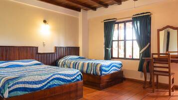 Quarto com duas camas de madeira, uma escrivaninha e uma cadeira.